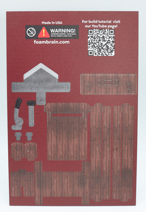Foam Brain Games Unassembled MDF board for Dice Guillotine. QR Code leading to youtube channel for assembly instructions, pieces of guillotine on a maroon background
